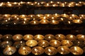 Many beautiful lit candles in a row glowing with a golden yellow light Royalty Free Stock Photo