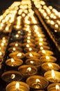 Many beautiful lit candles in a row glowing with a golden yellow light Royalty Free Stock Photo