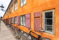 Many bicycles stands at color historical building in traditional style of Copenhagen, Denmark. Scandinavic city street