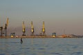 Many big cranes silhouette in the port at golden light of sunset. Mariupol, Ukraine