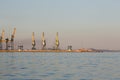 Many big cranes silhouette in the sea port of Azov at golden light of sunset. Mariupol Royalty Free Stock Photo