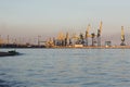 Many big cranes silhouette in the sea port of Azov at golden light of sunset. Mariupol