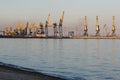 Many big cranes silhouette in the sea port of Azov at golden light of sunset. Mariupol