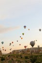 Many big hot air balloons flying over Cappadocia rocks in Turkey.
