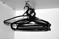 Many black hangers on a rod,  on white wall background. Royalty Free Stock Photo