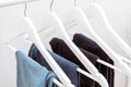 Many blue denim jeans hanging on white clothes hangers on clothing rack. Royalty Free Stock Photo