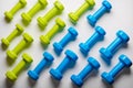 many blue and green dumbbells on a white background , concept preparing to fitness sports equipment top view mock up