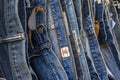 Many blue jeans hang on a rack. Jeans hanging in the store. Jeans or denim pants hanging on a hanger in a clothing store