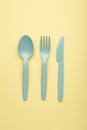 Many blue plasic forks, spoons and knives on yellow background Royalty Free Stock Photo