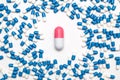 many blue-white capsules around one red-white capsule, large pill, medical drugs replacement concept