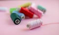 Many bobbins of bright sewing thread with a needle with a soft pink background Royalty Free Stock Photo
