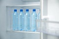 Many bottles with fresh water on fridge shelf