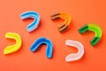 Many boxing mouthguards of different colors, lies on an orange background