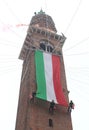 brave firefighter unroll italian flag on the ancient tower called Torre Bissara