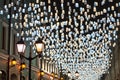 Many bright burning lights blue and yellow lanterns hanging on black night sky background closeup