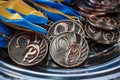 Many bronze medals with copper ribbons and yellow- blue ribbons on a silver tray, Champions awards, achievements in sport, the thi