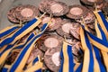 Many bronze medals with yellow blue ribbons on a silver tray