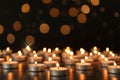 Many burning candles on table against dark background with blurred lights. Bokeh effect Royalty Free Stock Photo