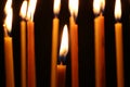 Many burning church candles on dark background, closeup