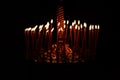 Many candles burning at night on the black background in church. Candle flame set isolated in black background. Group of burning Royalty Free Stock Photo