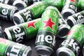 Many cans of Heineken alcoholic beer lie on a gray background.