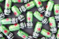 Many cans of Heineken alcoholic beer lie on a gray background.