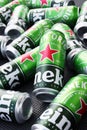 Many cans of Heineken alcoholic beer lie on a gray background.