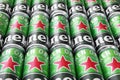 Many cans of Heineken alcoholic beer lie on a gray background.