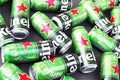 Many cans of Heineken alcoholic beer lie on a gray background.