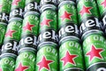 Many cans of Heineken alcoholic beer lie on a gray background.