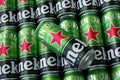 Many cans of Heineken alcoholic beer lie on a gray background.