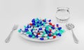 Many capsules of medicine are full of white plates with spoon and fork on a white background. The concept of taking medications or Royalty Free Stock Photo