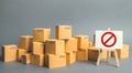 Many cardboard boxes and a sign stand with red symbol NO. Embargo, trade wars. Inability to sell products, ban on the import Royalty Free Stock Photo