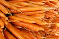 Many carrots arranged in a large stack at a farmers market.