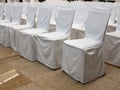 Many chairs in a row with white slipcovers