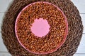 Many cherry stones on a pink plate with whole on a center, wicker carpet in the background Royalty Free Stock Photo