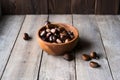 Many chestnuts in a wooden bowl and some scattered on the table