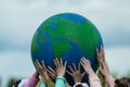 Many childrens hands hold planet earth