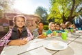 Many children sit at table with bright cups