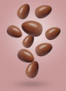 Many chocolate eggs falling on dusty pink background