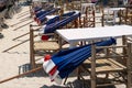 Many closed sun umbrellas on restaurant chairs prepared to be open up, morning time in beach restaurant behind sun lounge chairs. Royalty Free Stock Photo