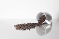 Many coffee coffee beans spilling out of a cup on a white counterspace with textspace and a reflection Royalty Free Stock Photo