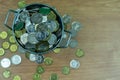 Many coins are in silver buckets on a green background. Money overflow from bucket. Coins overflow from silver bucket