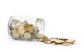 Many coins spilling out of a glass jar and isolated