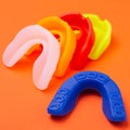 Many colored boxing mouth guards lie on an orange background