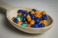 Many colored capsules in a spoon on a white table