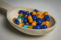 Many colored capsules in a spoon on a white table Royalty Free Stock Photo