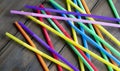 Many colored cocktail straws are scattered across the wooden table. On a wooden background are plastic straws for drinks Royalty Free Stock Photo