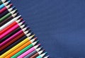 Many colored pencils diagonally in a row on a dark blue background. Top view, close-up, place for text. Creativity and education c Royalty Free Stock Photo