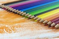 Many colored pencils lying on an orange Board